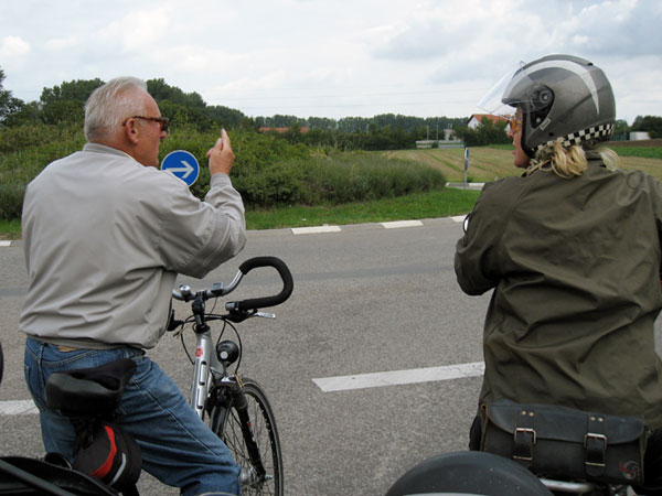 Gentleman on a bicycle points out the way to Sylvia on motorcycle