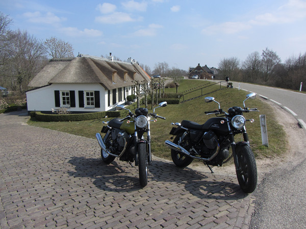 Two motorcycles in front of a house on a dyke