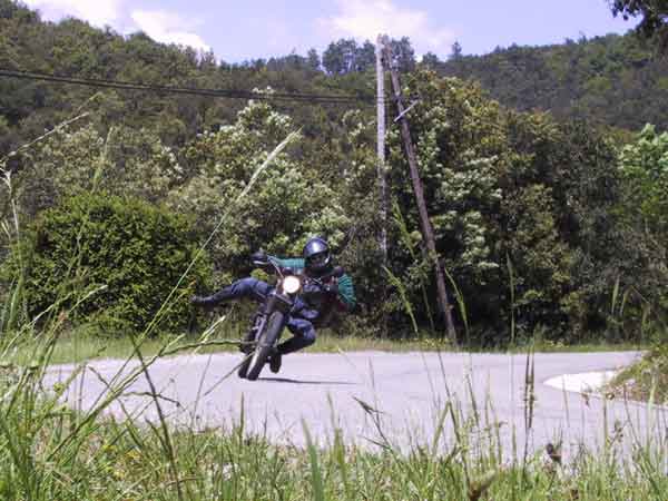 Motorcyclist like a clown in the corner, sticking out his outside leg