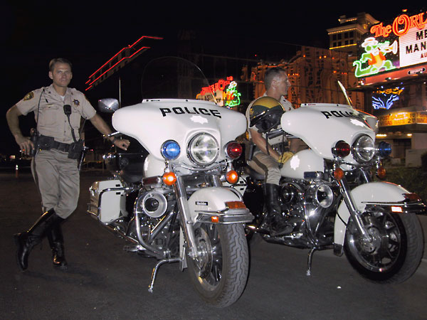 Two motorcops standing next to their Harleys