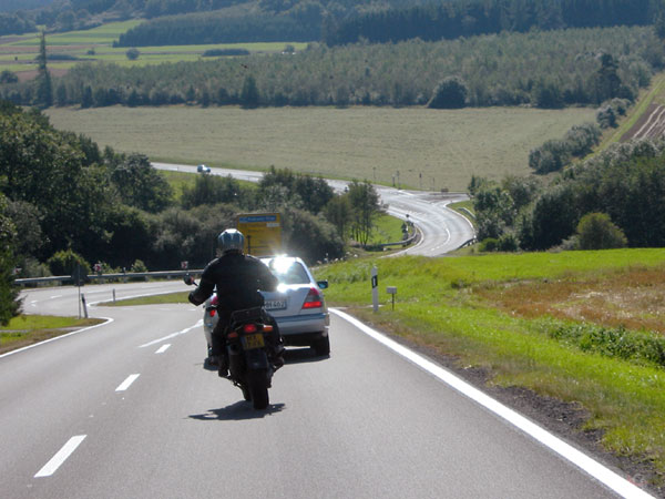 Motorcycle rider rides up to just behind a car