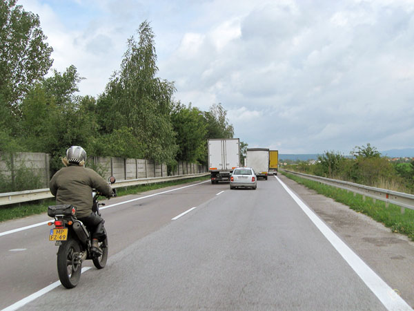 Motorcycle rider behind a truck which overtakes another truck
