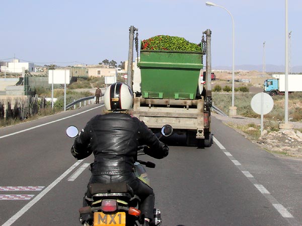 Motorbike behind a truck loaded with peppers