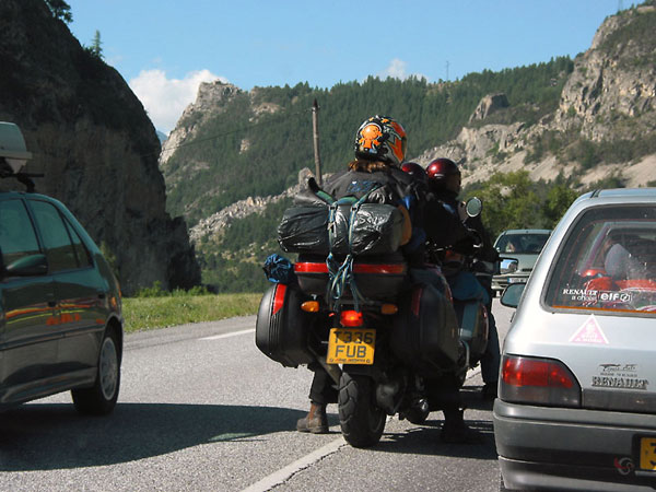 Motorcycle (with much luggage) tightly between cars