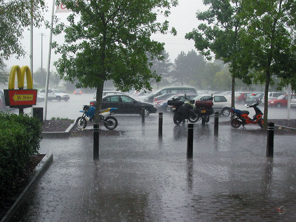 Two motorcycles in the street, in a downpour